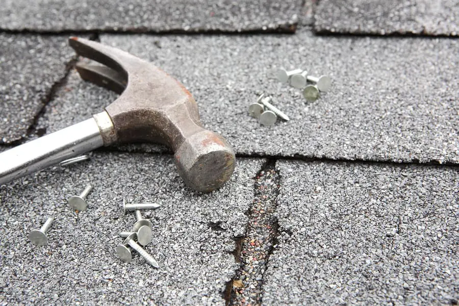 hammer and nails on asphalt shingle roof