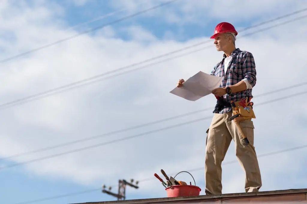 Roofing professional looking over a roof with a clipboard