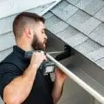 Technician installing rain gutters on a home