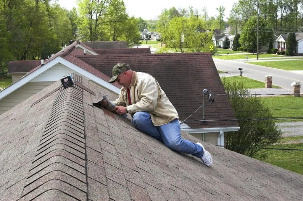 man on roof repairing asphalt shingles