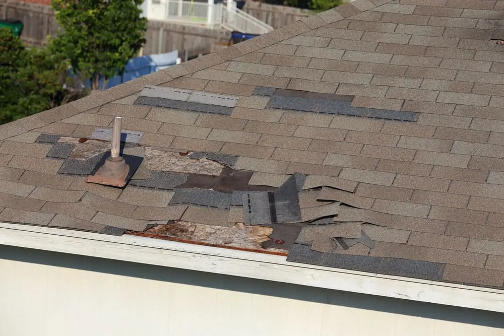 A close up view of shingles being blown off a roof and other roof damage in Albert lea, MN