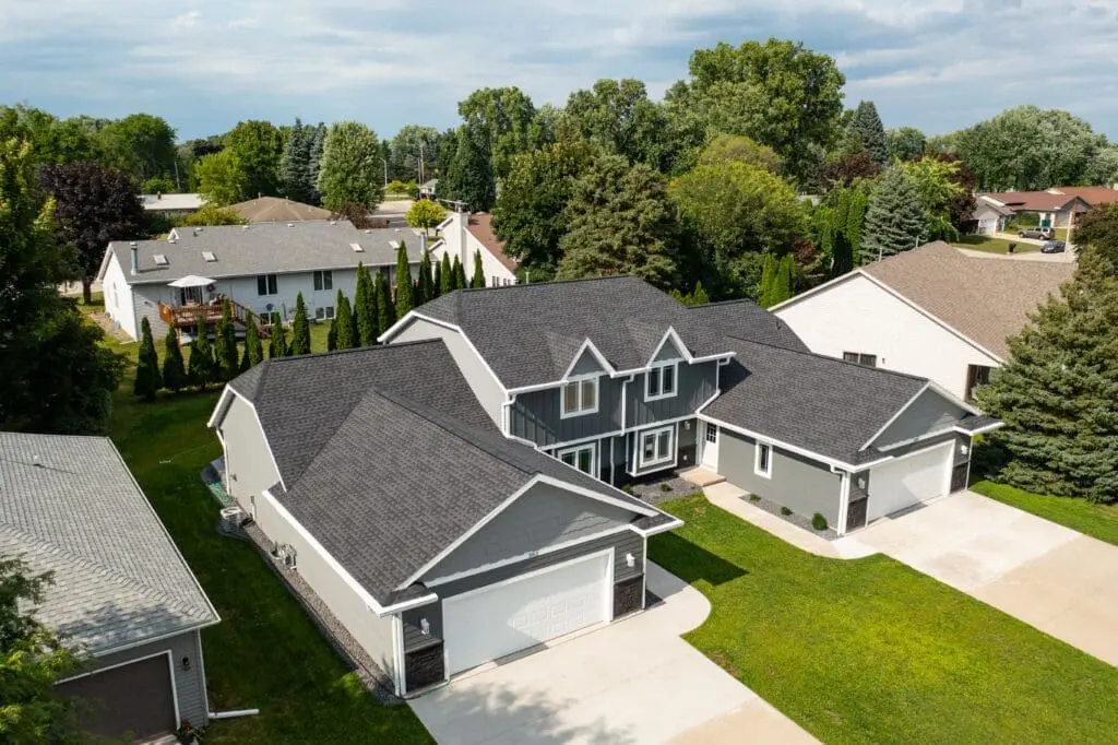 suburban home with new asphalt shingled roof and two garages