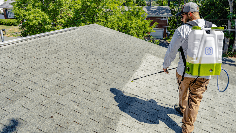 person spraying an asphalt shingle roof with Go Nano roof coatind