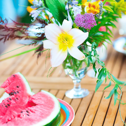 Table with watermelon slices and a flower bouquet