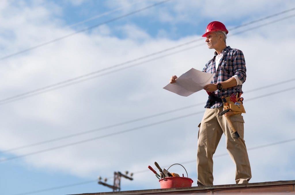 Roofing professional looking over a roof with a clipboard