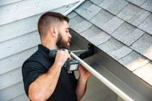 Technician installing rain gutters on a home
