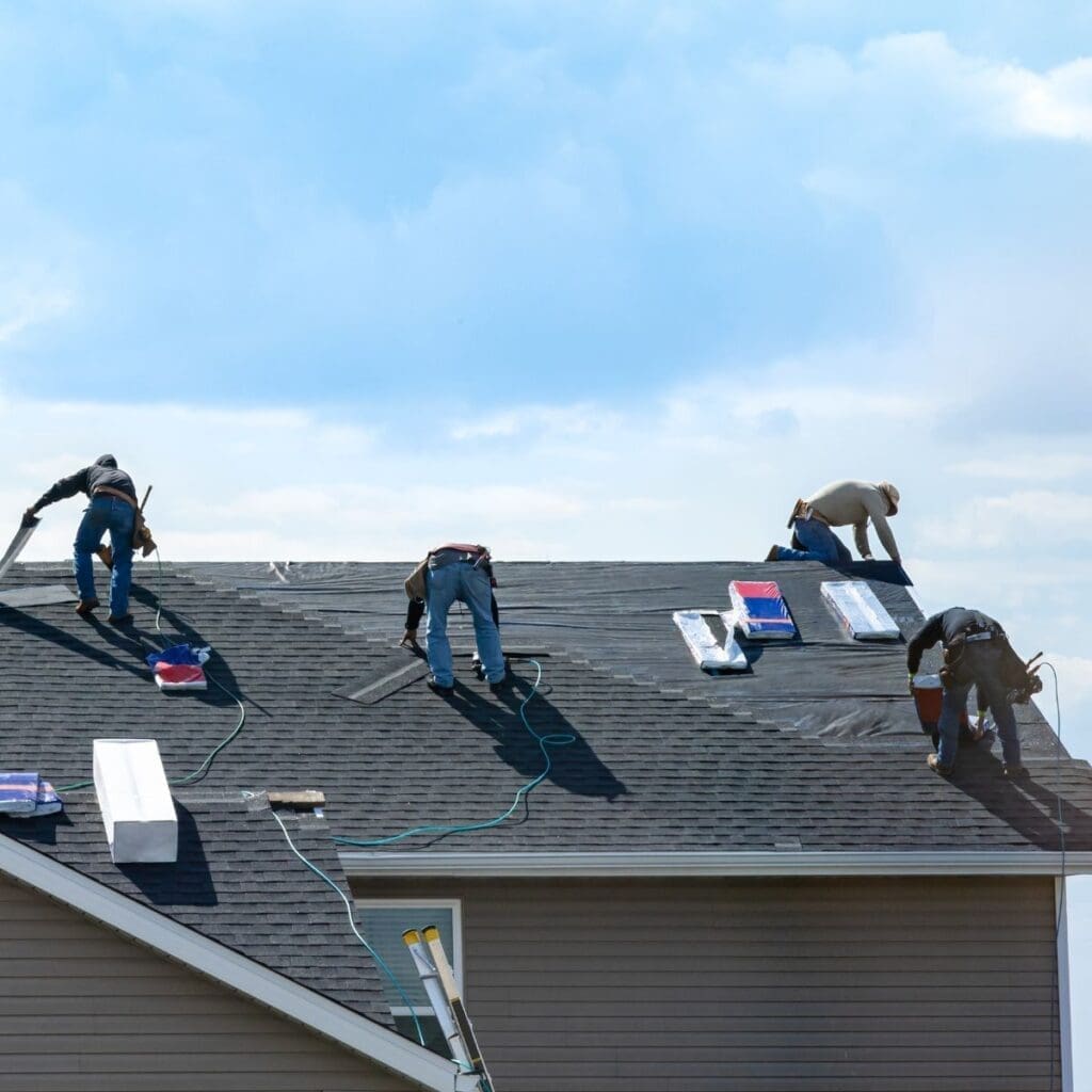 four men working on an asphalt shingle roof