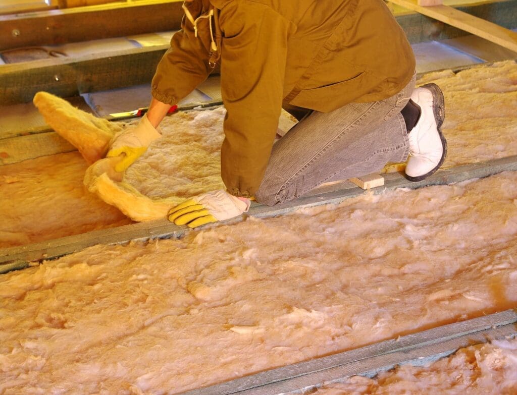person installing insulation in an attic